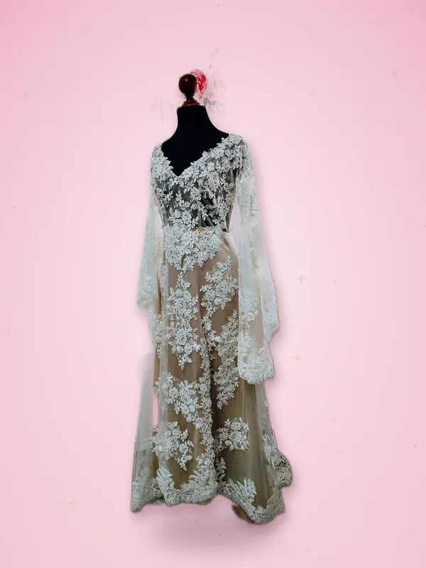 Vestido de novia de encaje floral sobre fondo nude con mangas largas